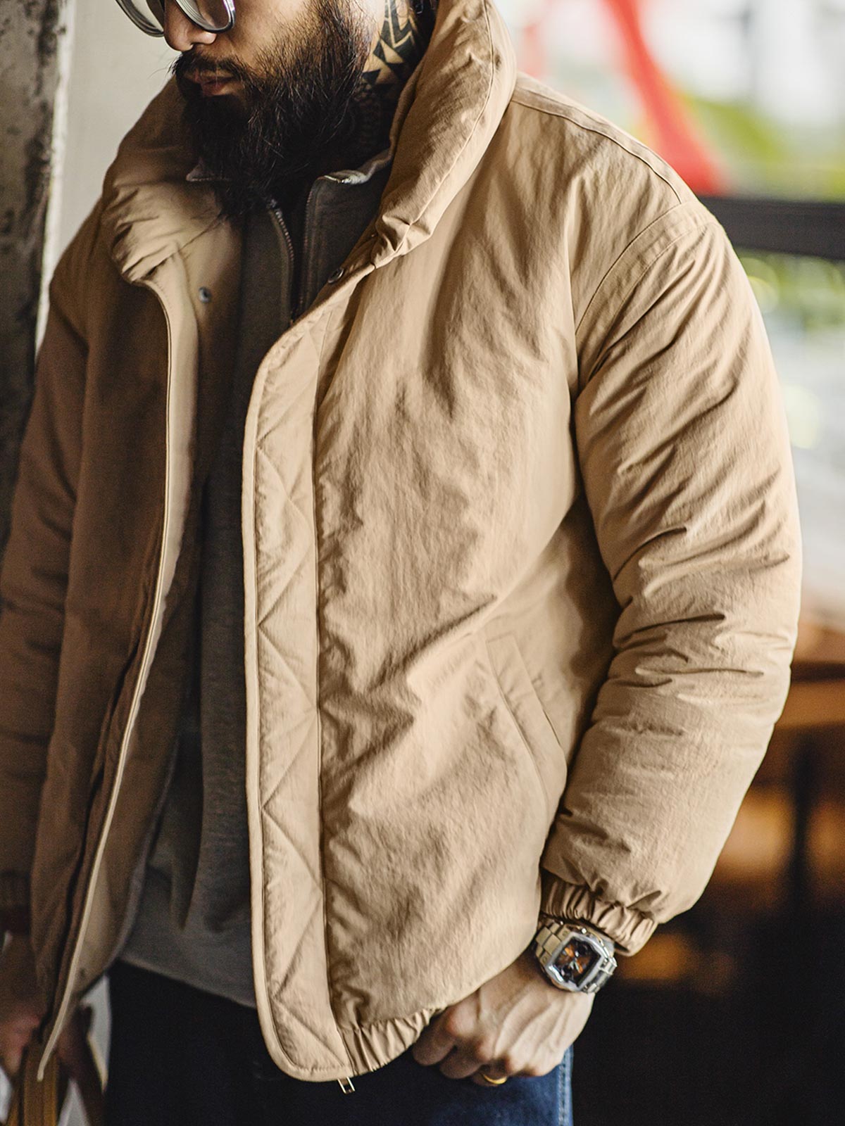 詳細画像: ブロンズカラーのジッパーとテーラード襟のディテール。スタンドカラーとリフレクター付きロゴで機能性を強化
モデル画像: モデルが着用したレトロ風中綿ジャケットの全身スタイリング。通勤やアウトドアにも最適な防寒アイテム