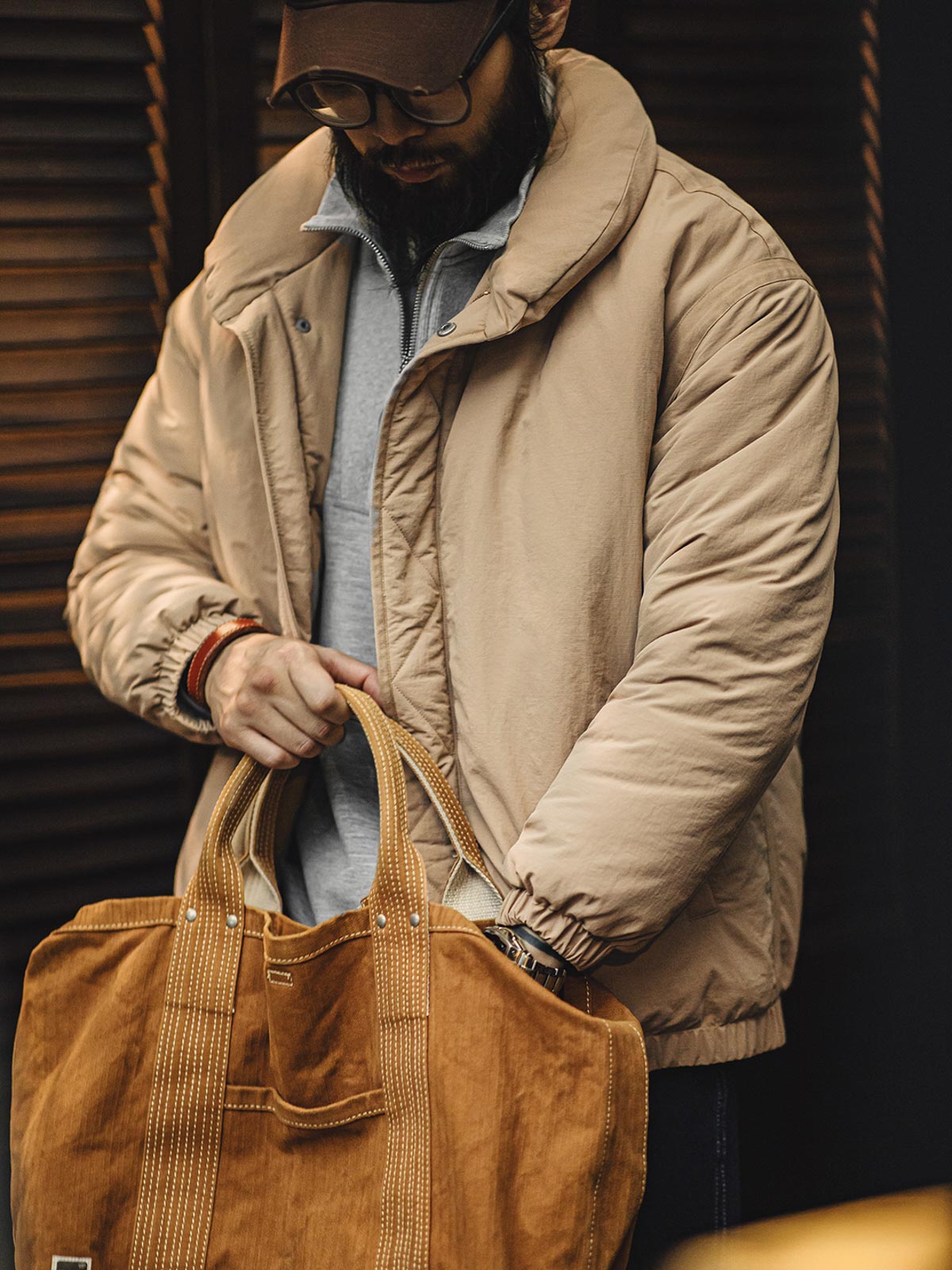 詳細画像: ブロンズカラーのジッパーとテーラード襟のディテール。スタンドカラーとリフレクター付きロゴで機能性を強化
モデル画像: モデルが着用したレトロ風中綿ジャケットの全身スタイリング。通勤やアウトドアにも最適な防寒アイテム