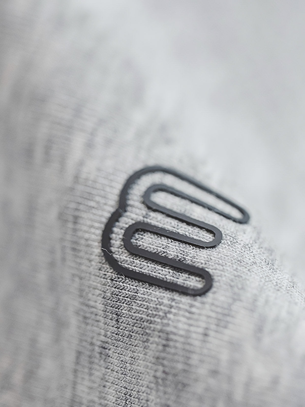 グレーショート丈フーディーのスノーフレークパターンとジッパーのディテール特写