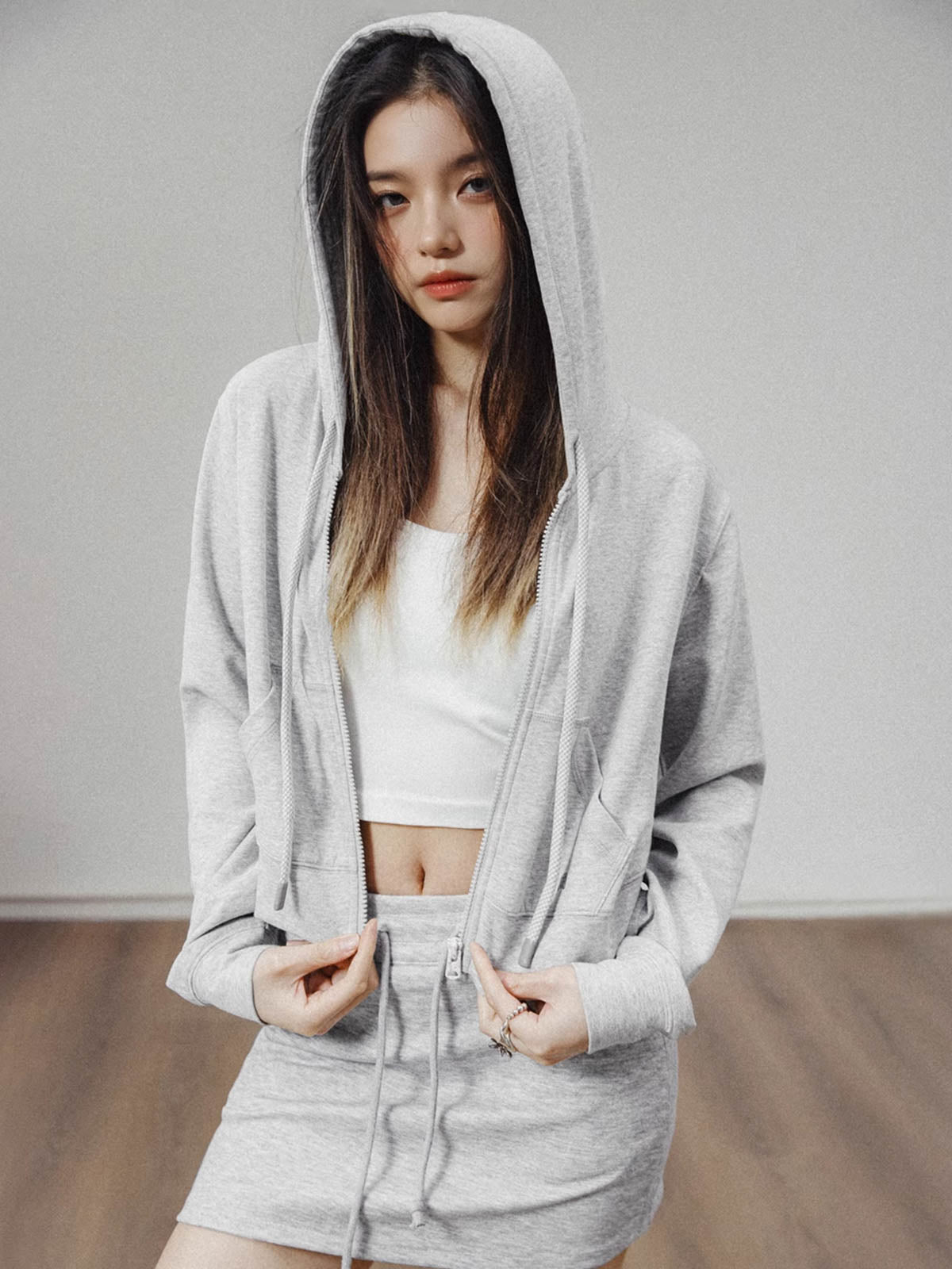 モデルがアメリカンストリートスタイルのグレーショート丈フーディージップアップを着用し、多様なスタイリングを披露