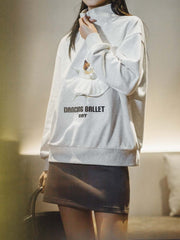 モデルがPESSOA CLUBのグレー「バレエキャット」スウェットシャツを着用し、リラックスフィットのスタンドカラーとハーフジップデザインを披露