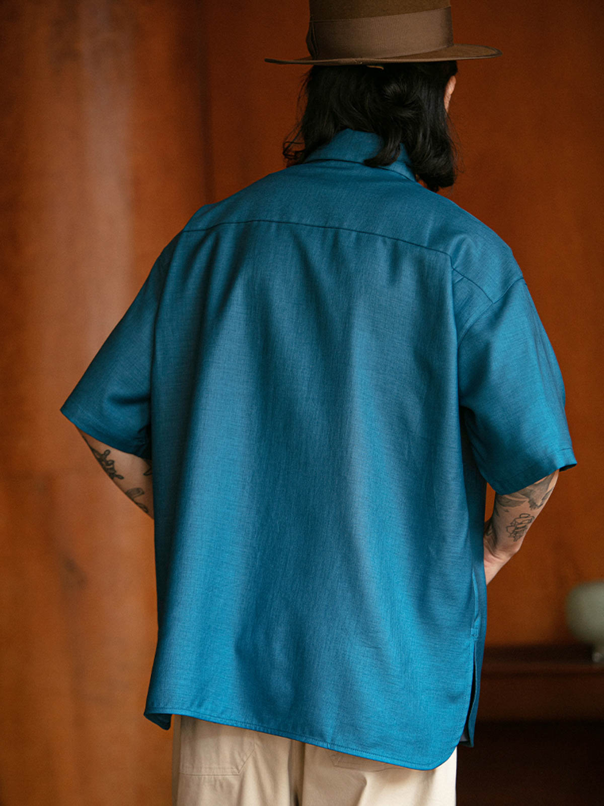 モデルがフラップポケットプリント半袖シャツを着用し、ライトカラーのパンツとコーディネート