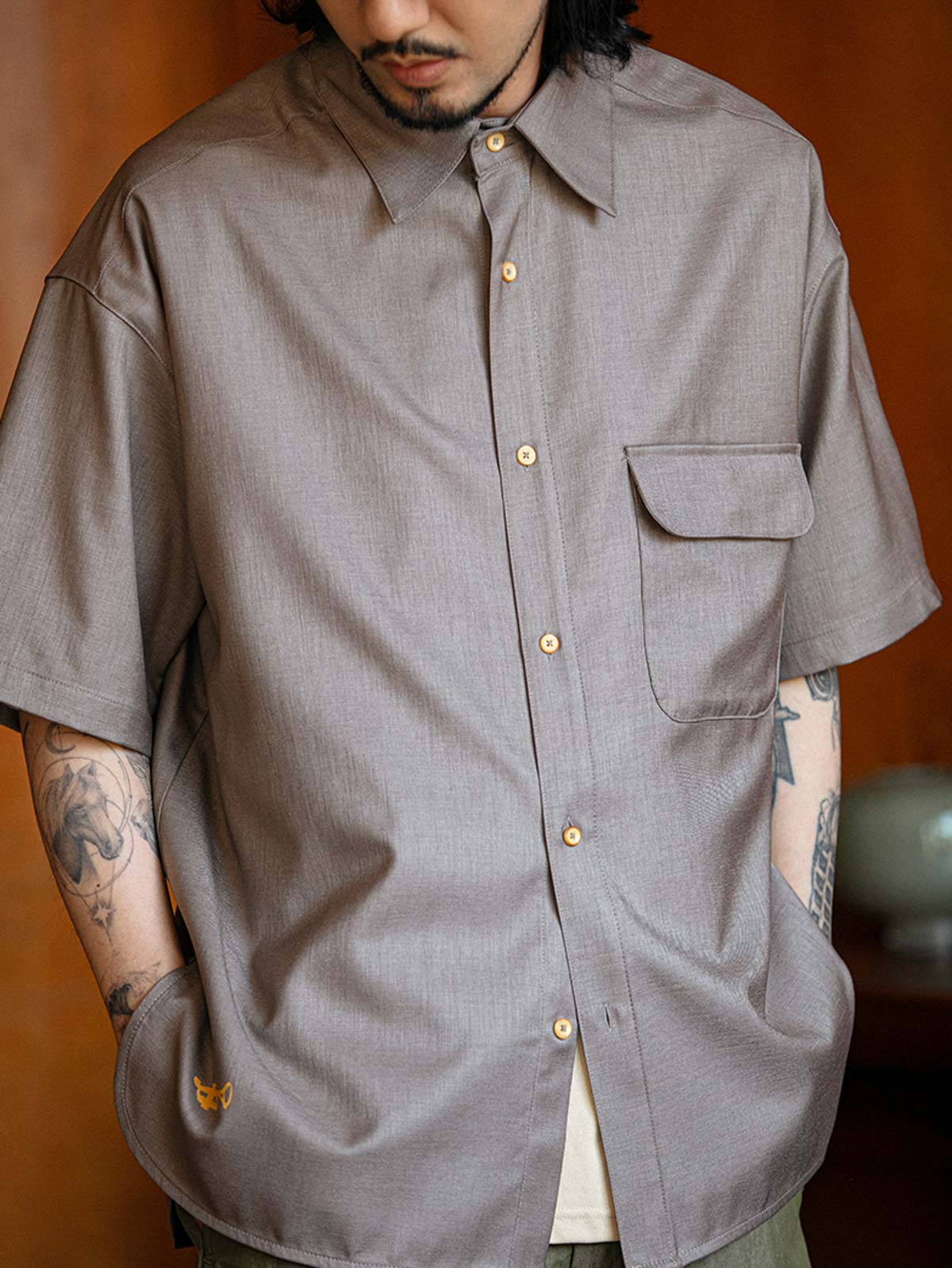 モデルがフラップポケットプリント半袖シャツを着用し、ライトカラーのパンツとコーディネート