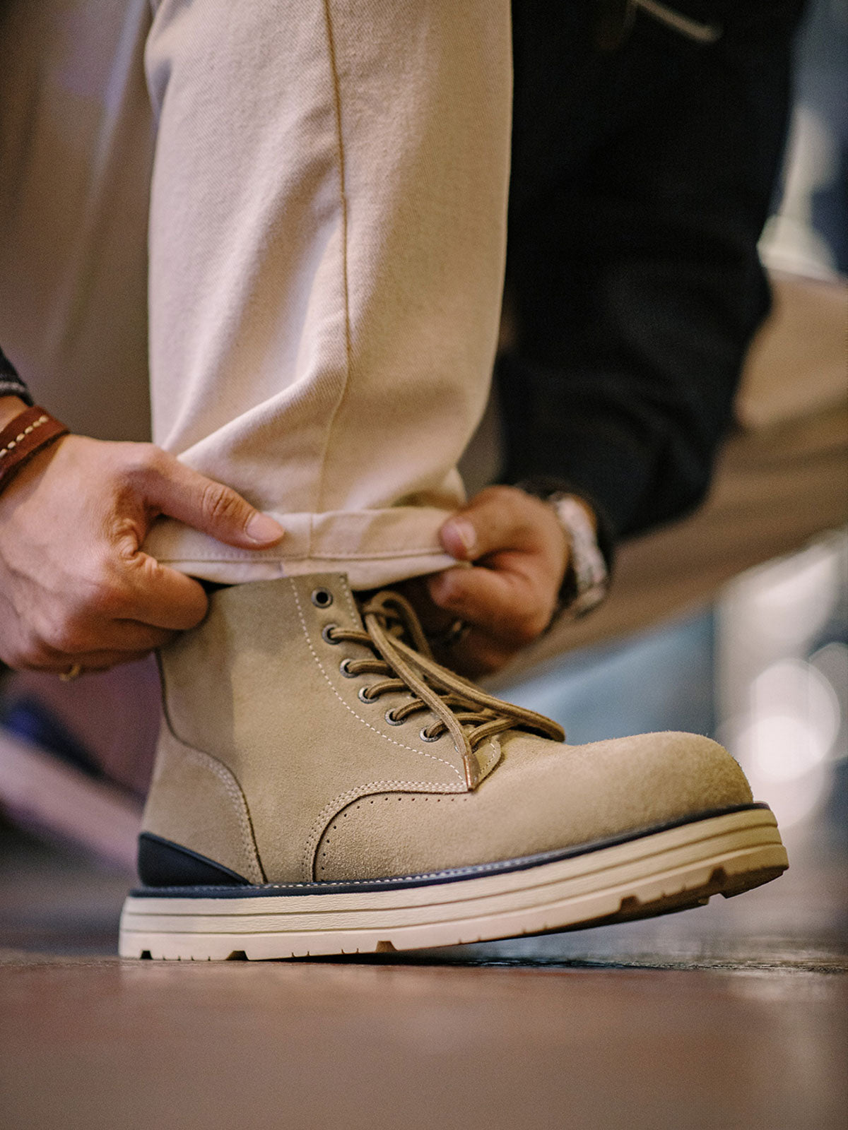 製品画像: 厳選された牛革スエードと特注厚底デザインを組み合わせたヴィンテージ感漂うワークブーツ全体像、グラベルカラーのトーンが特徴。
詳細画像: 牛革スエードのアッパー、PUレザー靴舌、白いステッチが際立つラバーディテールのクローズアップ。