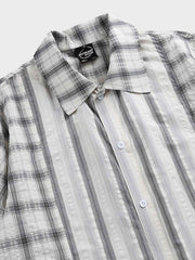 ストライプとチェックのパッチワークデザインを特徴とする半袖シャツのクローズアップ。