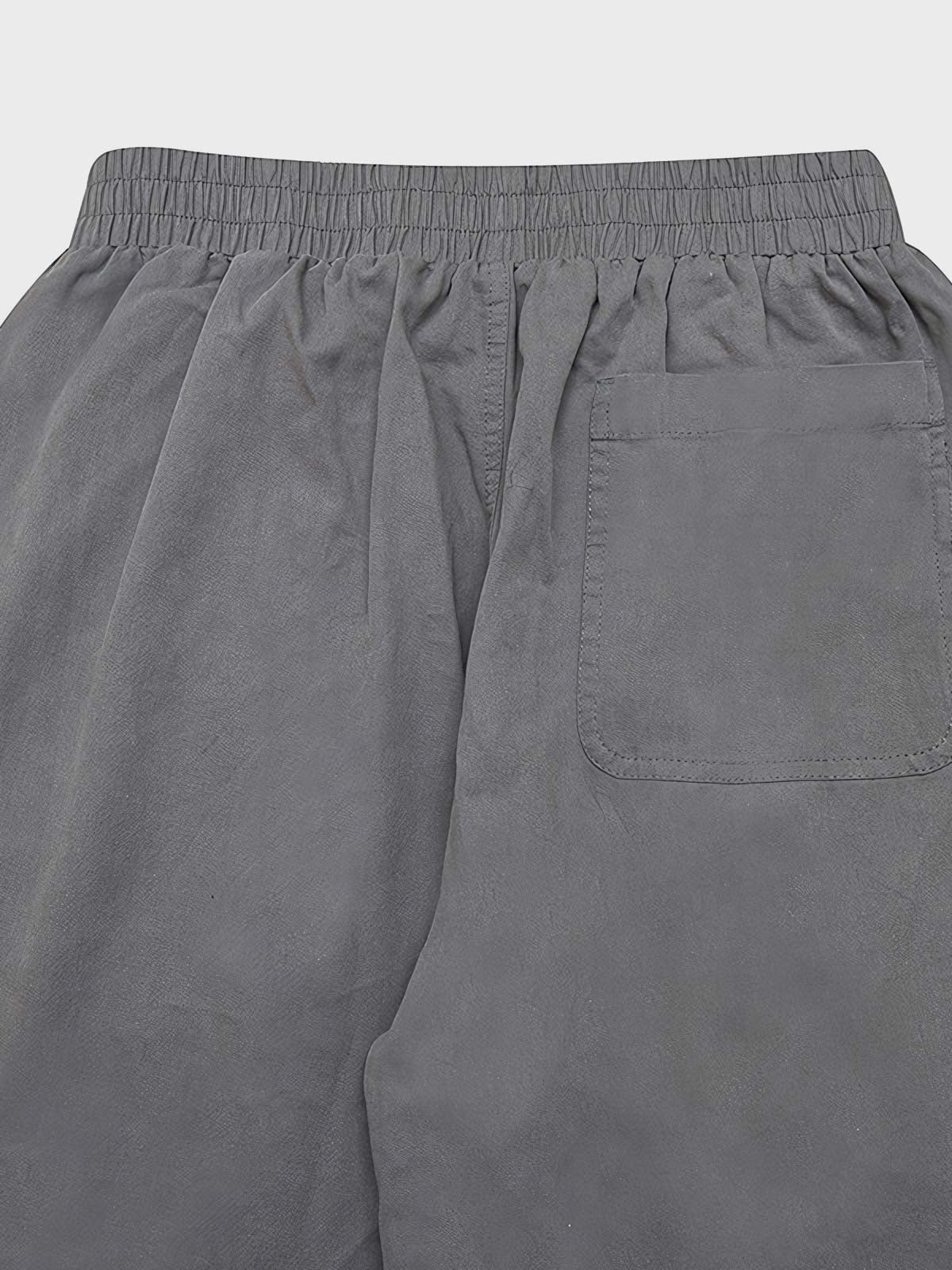 カジュアルパンツのドローコードとパッチワークディテールのクローズアップ。素材の耐久性と細部の工夫が見て取れる、機能的でスタイリッシュなデザイン。