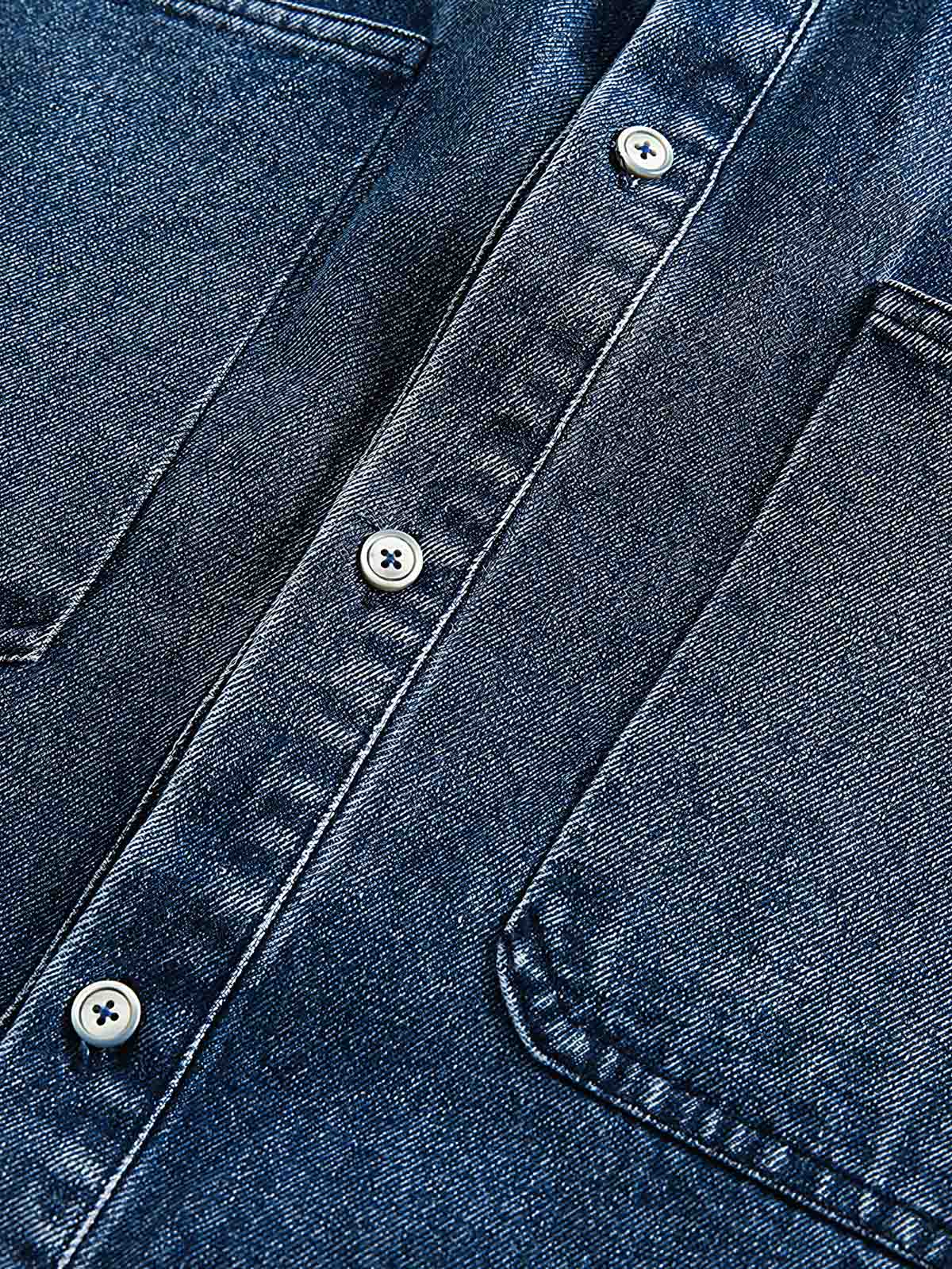 デニム半袖シャツの細部のクローズアップ、精巧なステッチとクラシックなボタンが見える。質感が豊かで、着用するほどに個性が現れる高品質デニム生地が特徴。
