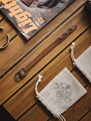 茶色のレザーブレスレット、幅広のベルトとヴィンテージ加工されたバックルが特徴的