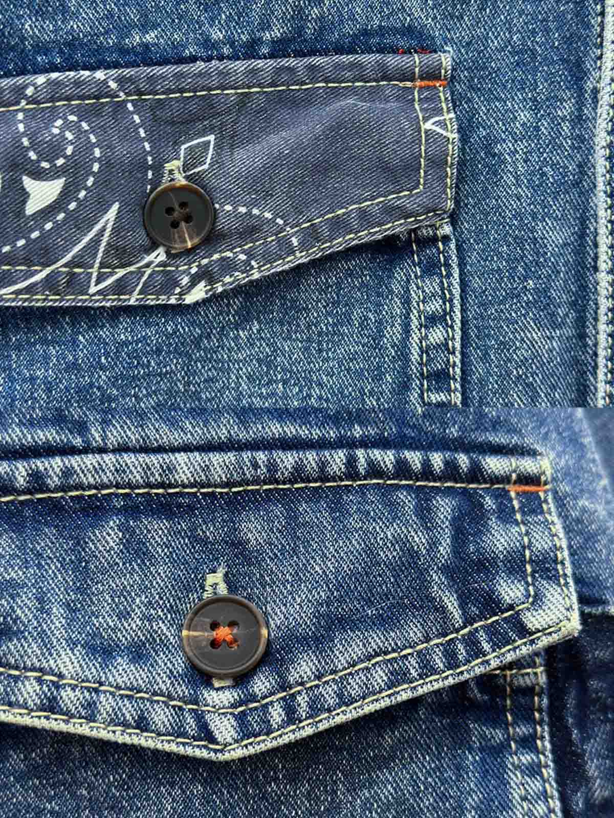 デニムシャツの袖口にあるタイスリーブノットとポケットのステッチラインのクローズアップ。手作業の細かなデテールが強調されている。