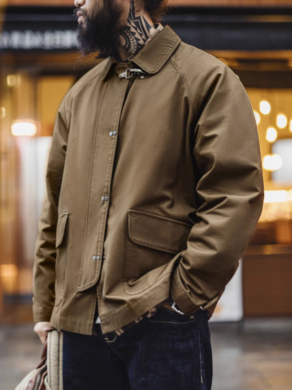 詳細画像
金属製ロブスタークランプとラグランスリーブのディテール、背中の中央縫い合わせデザイン、ブラウンコットン素材で厚手で耐久性があり、通気性も確保

モデル画像
消防バックルキャンバスジャケットを着用したモデル、ユニークなロブスタークランプとラグランスリーブのデザイン、快適で活動的な着心地を提供するルーズフィットスタイル