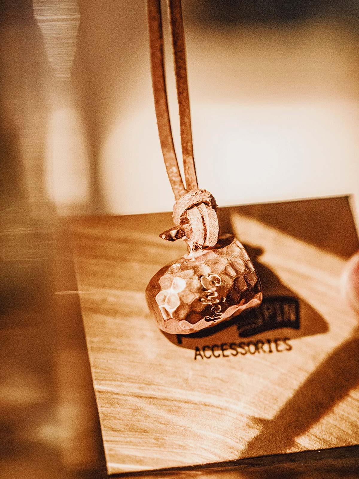 製品画像
ハンドメイドで仕上げられたハンマーテクスチャーが美しい銅カップペンダント。全体的にヴィンテージ感を強調したデザインで、時間の経過とともに味わい深いアンティークな色合いが楽しめます。レザーコード付きでカジュアルからフォーマルまで幅広く対応可能なアクセサリー

詳細画像
職人の手作業によるハンマーテクスチャーのディテールと、丁寧に彫刻された英文字刻印が印象的な銅カップペンダント。細部にまでこだわりが詰まった表面デザインが、独自のクラフトマンシップを感じさせます。自然な酸化による変化が楽しめる素材感も魅力