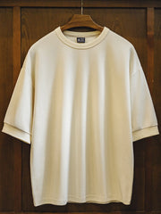 ゆったりとしたドロップショルダーTシャツ、背面上部に同色の波形刺繍が施されている