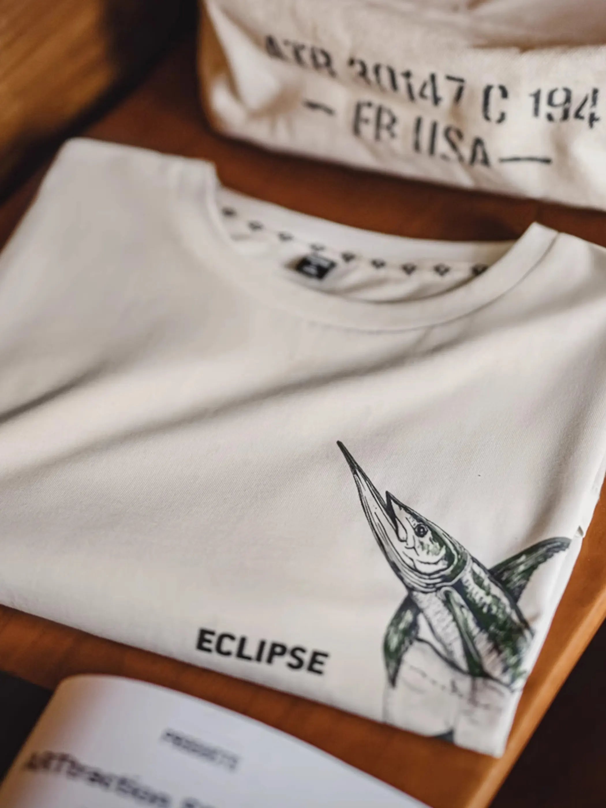 ポケット位置にマーリン錯視プリントを配したホワイトTシャツ