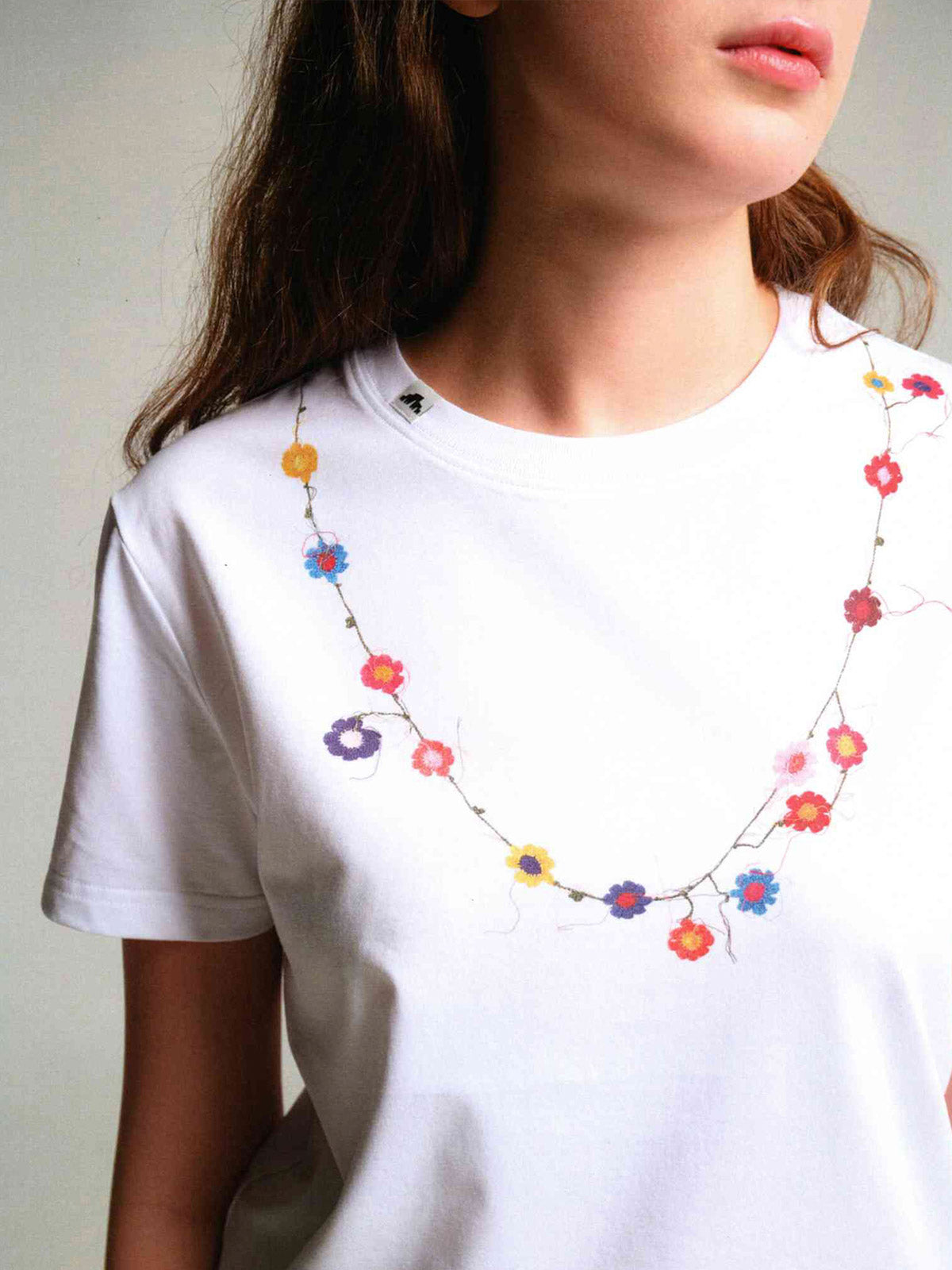 詳細画像: フラワーバッドネックレスTシャツの詳細図、精緻な花蕾刺繍とリブ付きクルーネックを展示