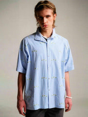 モデル画像: モデルが着用した花柄刺繍シアサッカーシャツの展示図、シャツのシルエットとスタイリングを紹介