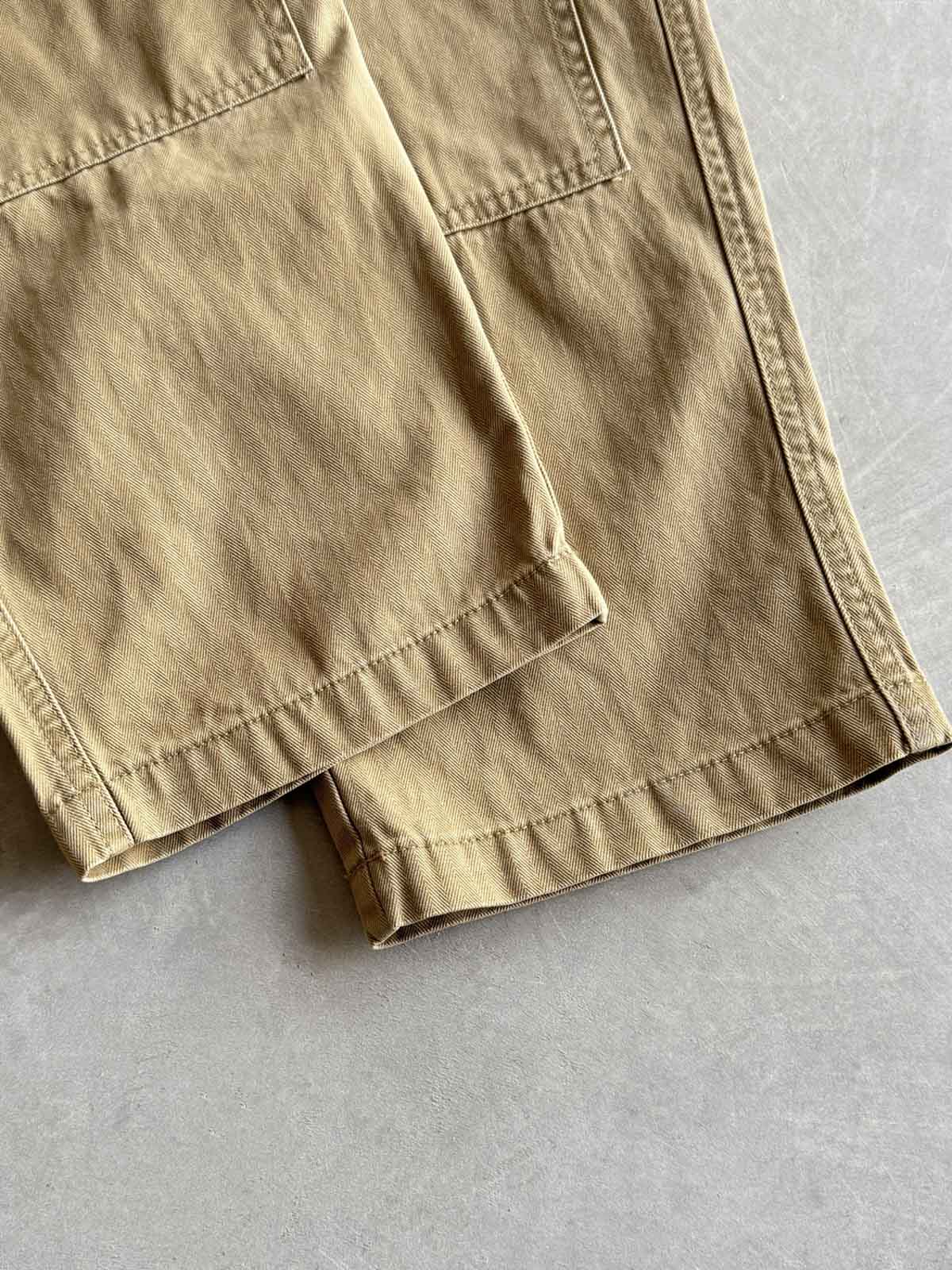 製品画像
「ヘビーウォッシュ加工が施されたヘリンボーン柄コットン素材のアメカジワークパンツ全体イメージ。自然な色褪せやダメージ感、パッチワークディテールが特徴。」

詳細画像
「ヘリンボーン柄コットン素材とヘビーウォッシュ加工によるダメージデザイン、パッチワークディテールをクローズアップ。YKK純銅ジッパーが耐久性を高める。」