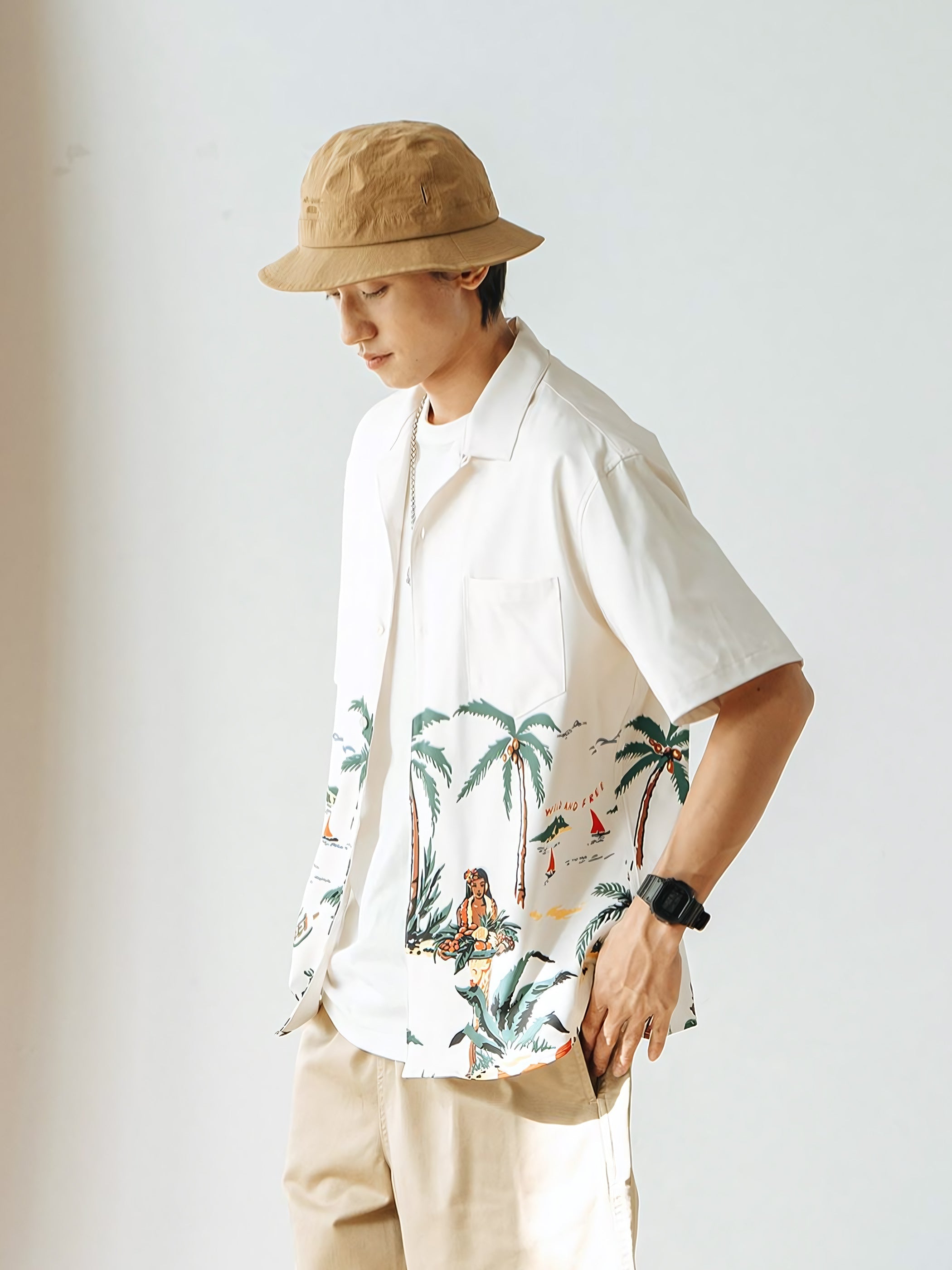 モデルが着用するビーチとヤシの木のレトロなハワイ風景プリントのアロハシャツ、自然で快適な着心地を示す。