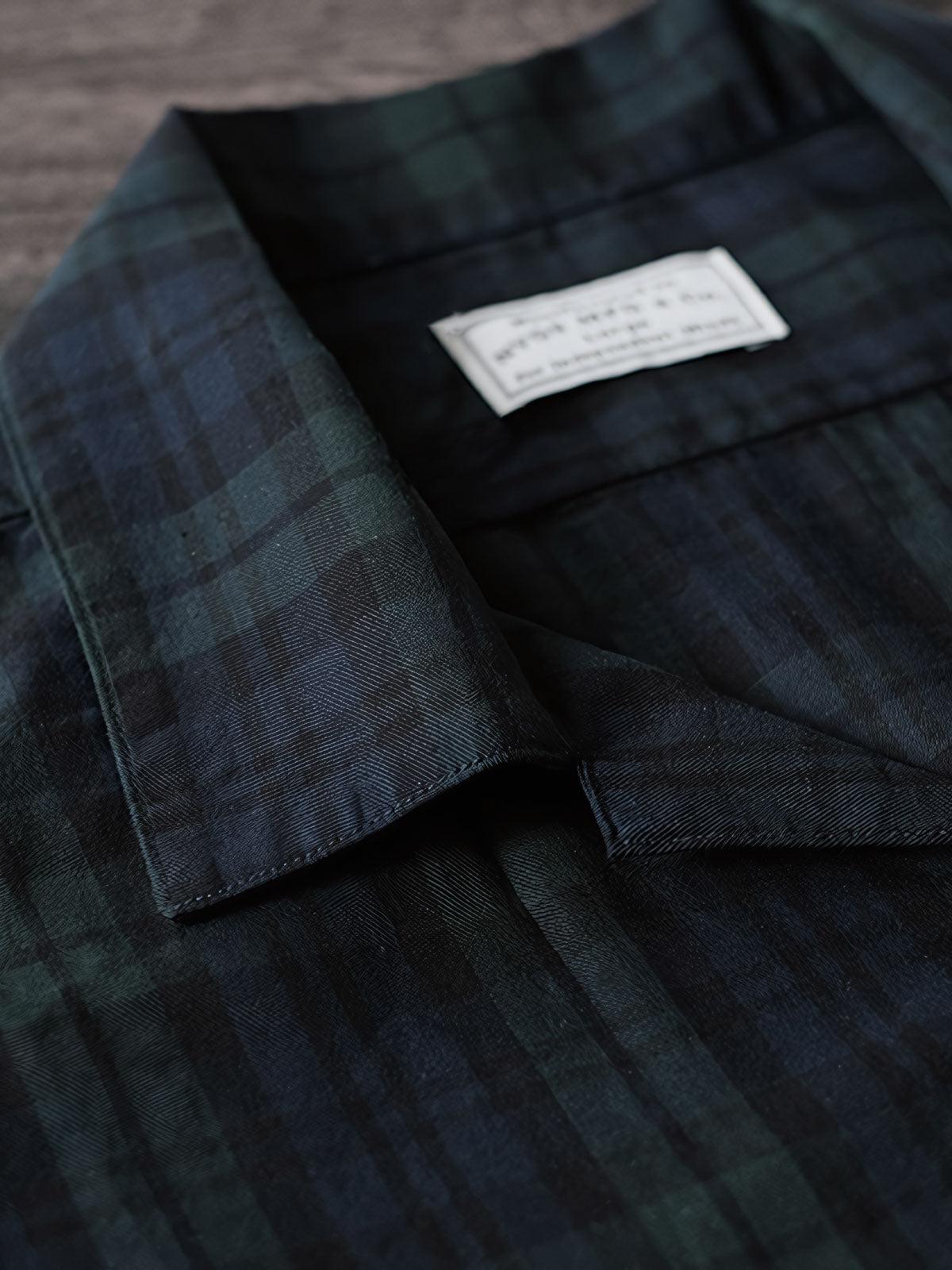 シャツのダークグリーン＆ネイビーチェックのディテールとナチュラルキャッツアイボタンのクローズアップ