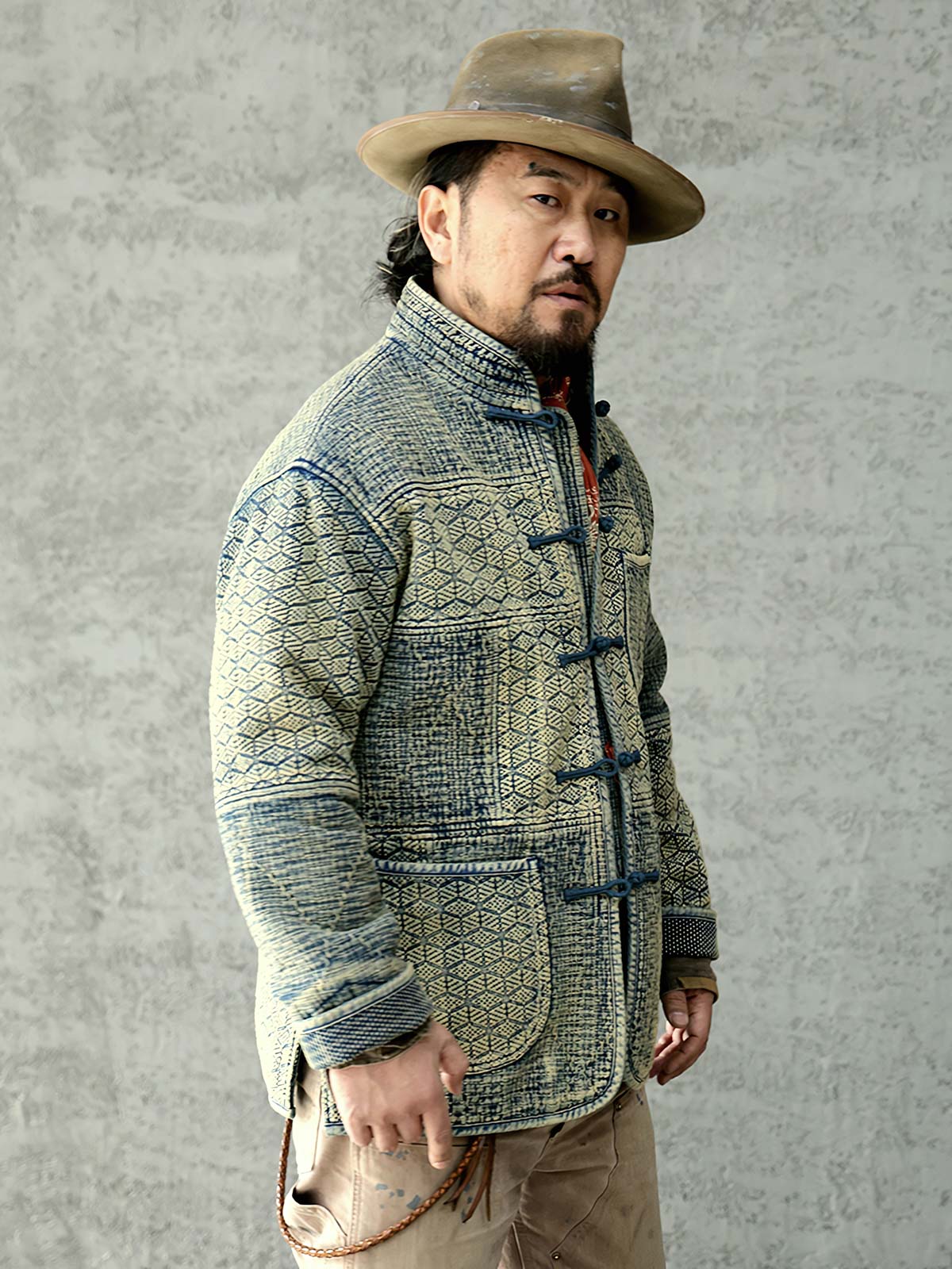 詳細画像: 刺子織りの繊細なテクスチャと藍染めの深みある色合いを強調したディテール写真。水洗抜染加工による個性的な風合いを表現。
モデル画像: 藍染め刺子織りスタンドカラージャケットを着用したモデルによる、レトロで上品なスタイリング写真。