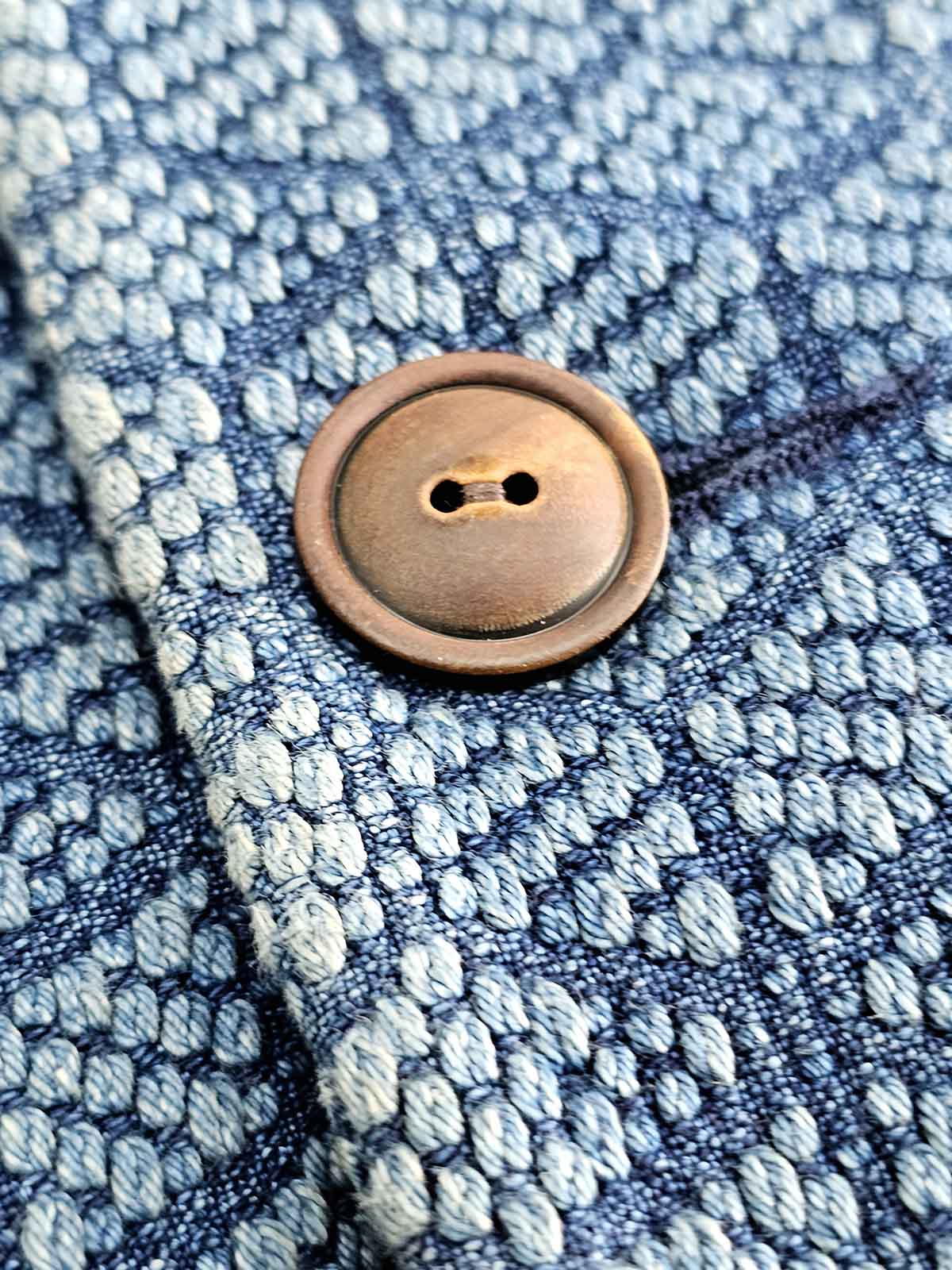 ジャケットの裾のコントラストカラーと木製ボタンの詳細