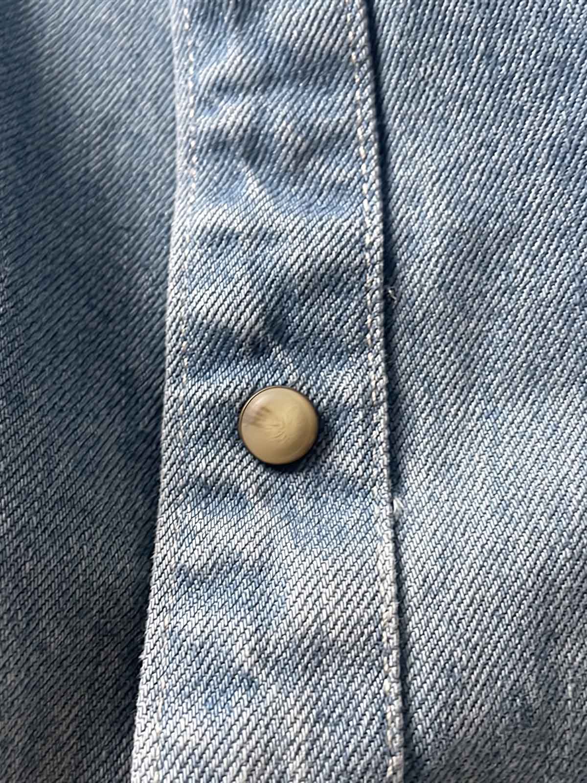 製品画像: 古着風加工の破れ水洗いヴィンテージデニムシャツ正面画像、ヴィンテージ感が際立つ。
詳細画像: ワークポケットと摩耗加工のディテール画像、クラシックな雰囲気を強調。