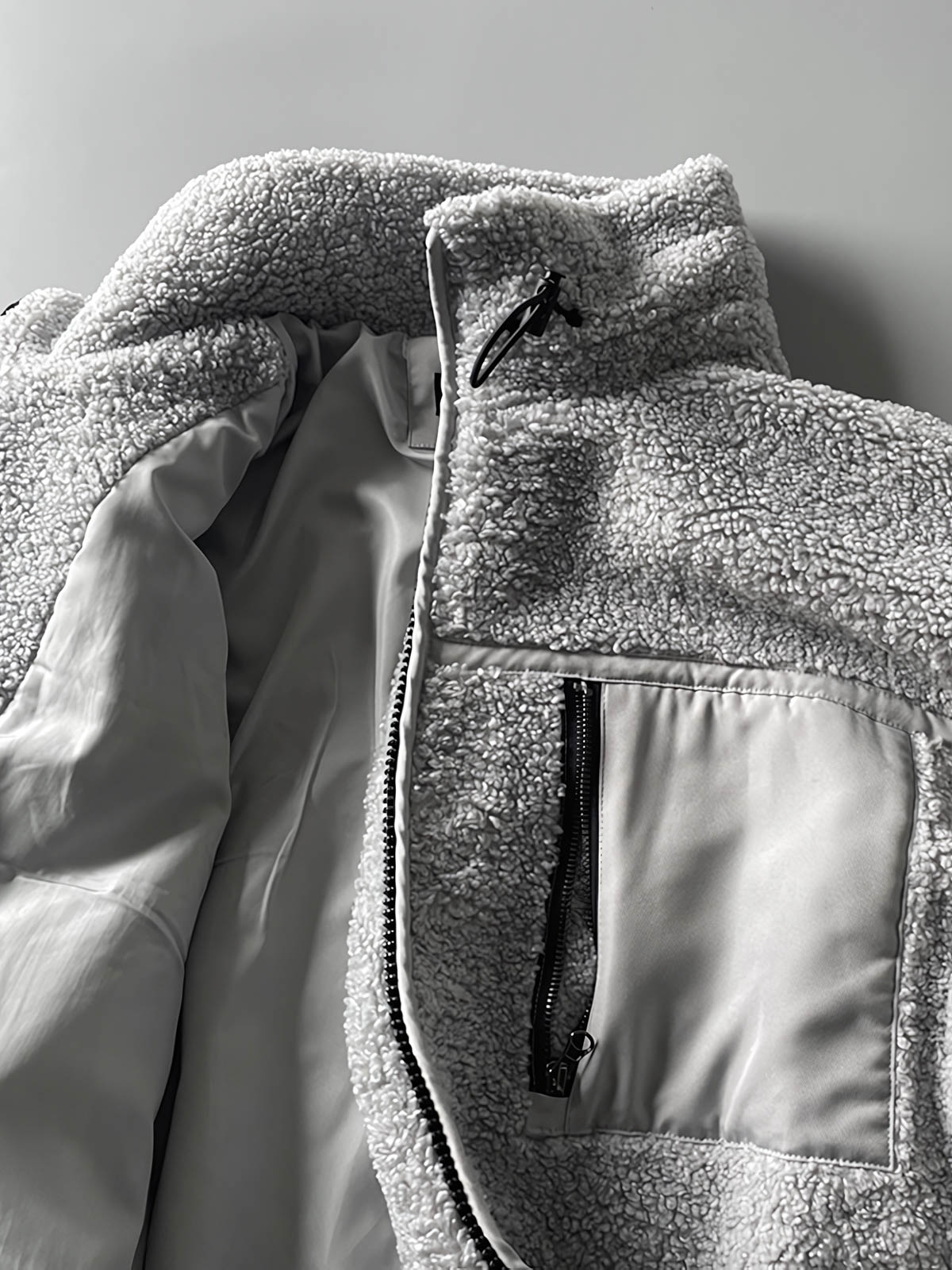 製品画像: ボアフリーススタンドカラージャケットの全体画像、アウトドアやカジュアルスタイルに対応。
詳細画像: 胸元ジッパーポケットのディテール画像、実用性とデザイン性を強調。