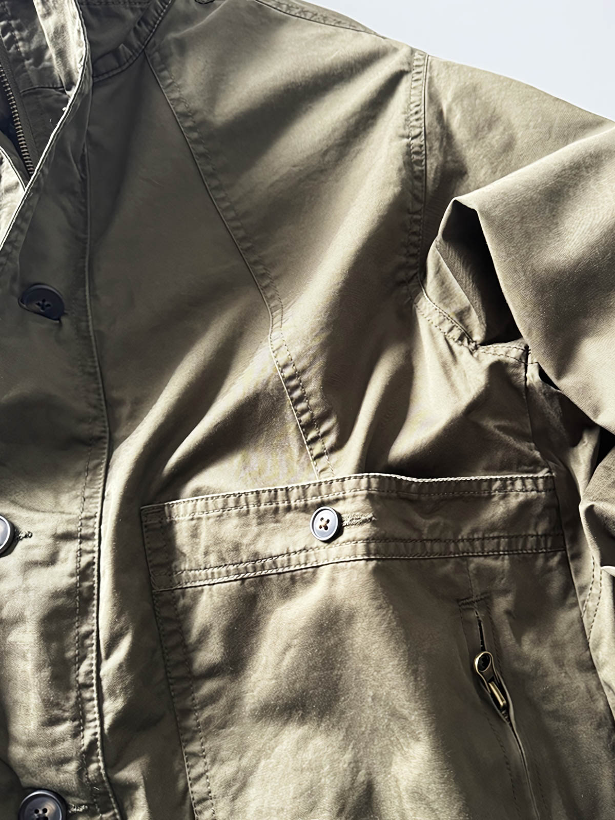 製品画像: オレンジカラーのダブルスタンドカラーワークジャケットの正面画像、実用的でスタイリッシュなデザインが特徴。
詳細画像: 袖部のジッパーポケットとスタンドカラーデザインのディテール画像、ワークスタイルを強調。