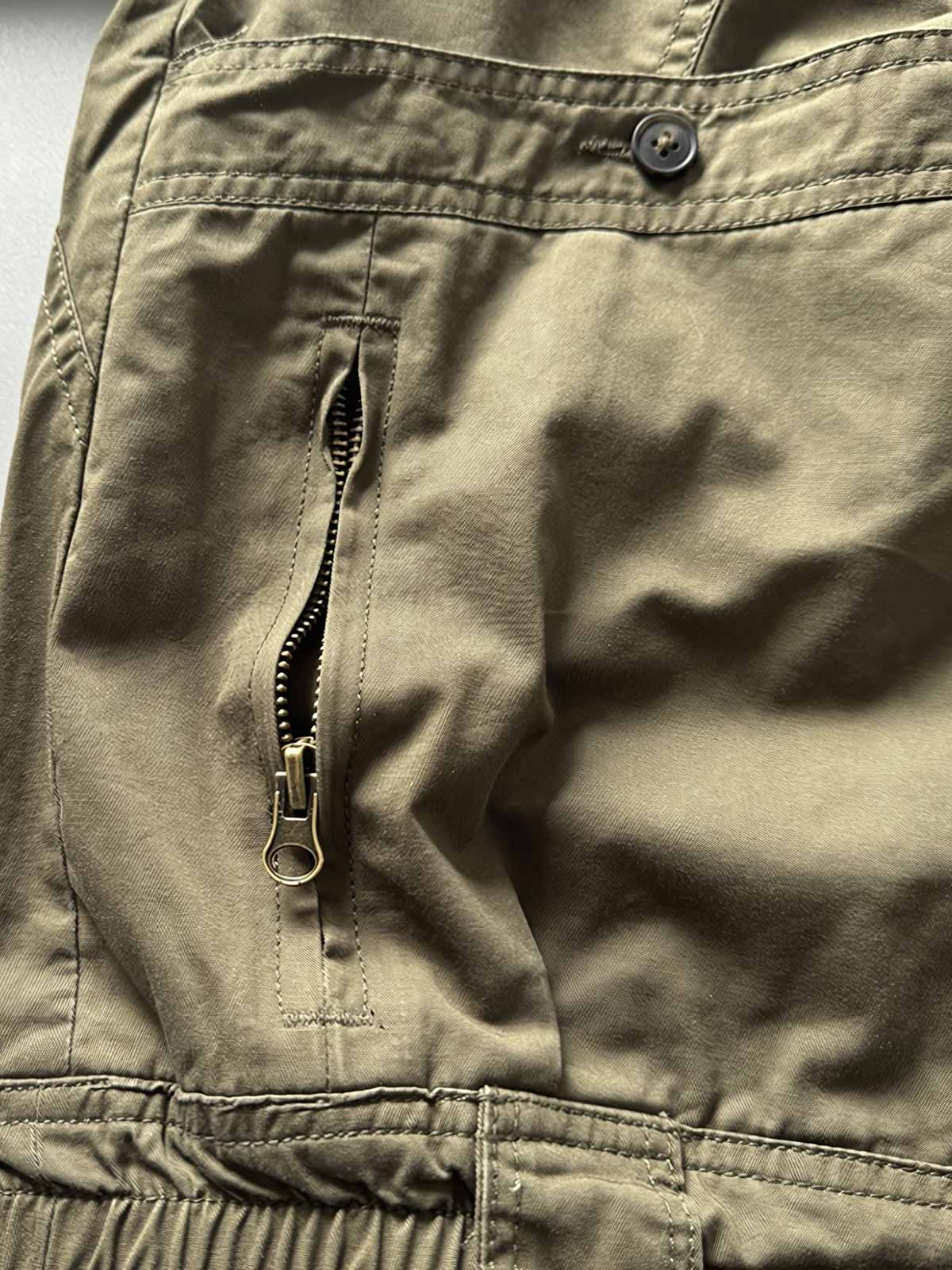 製品画像: オレンジカラーのダブルスタンドカラーワークジャケットの正面画像、実用的でスタイリッシュなデザインが特徴。
詳細画像: 袖部のジッパーポケットとスタンドカラーデザインのディテール画像、ワークスタイルを強調。