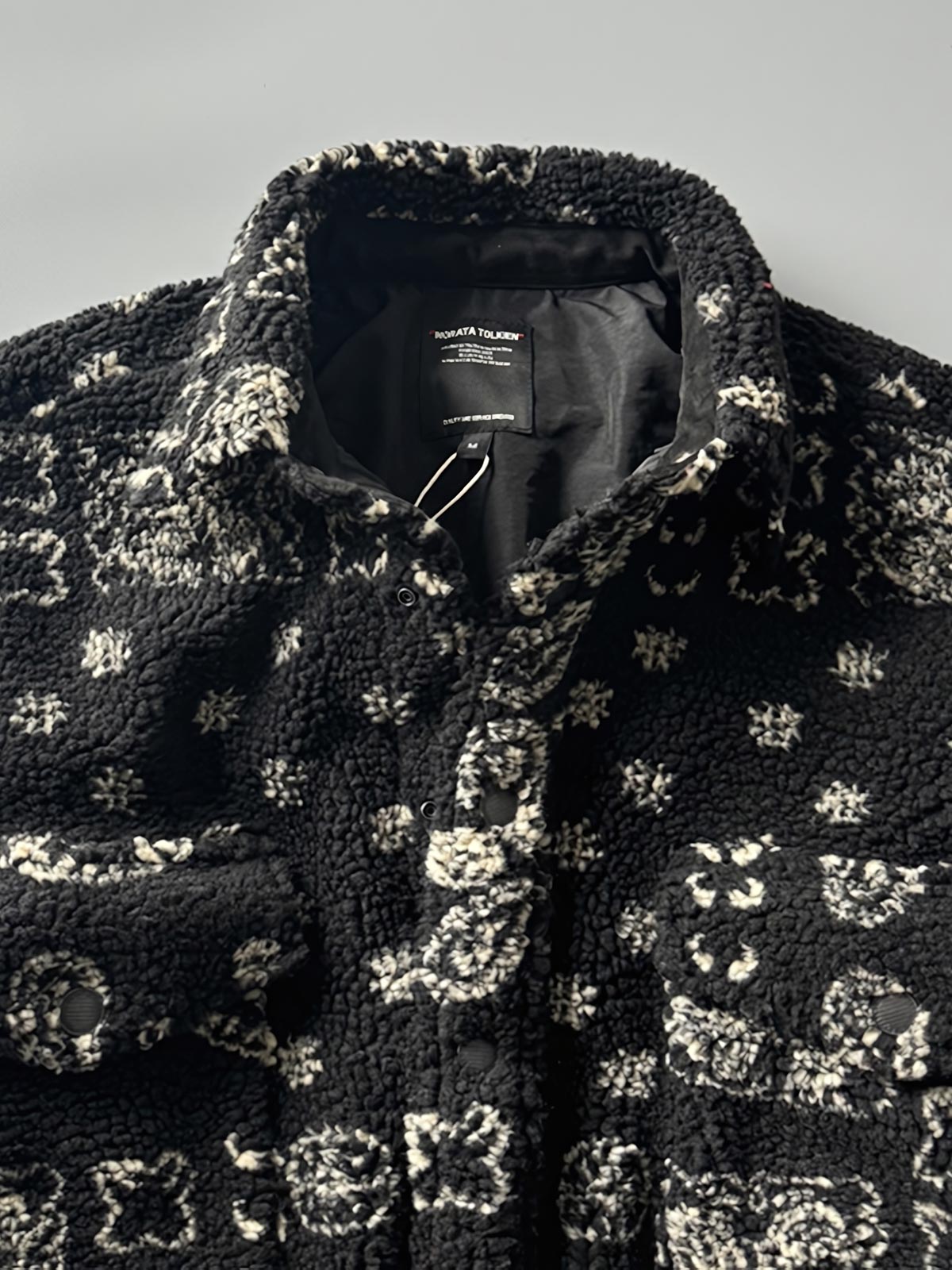 製品画像: ヴィンテージトライバルパターン シープボアシャツの正面画像、トライバルパターンが際立つデザイン。
詳細画像: シープボア素材とトライバルパターンのディテール画像、ヴィンテージ感を強調。