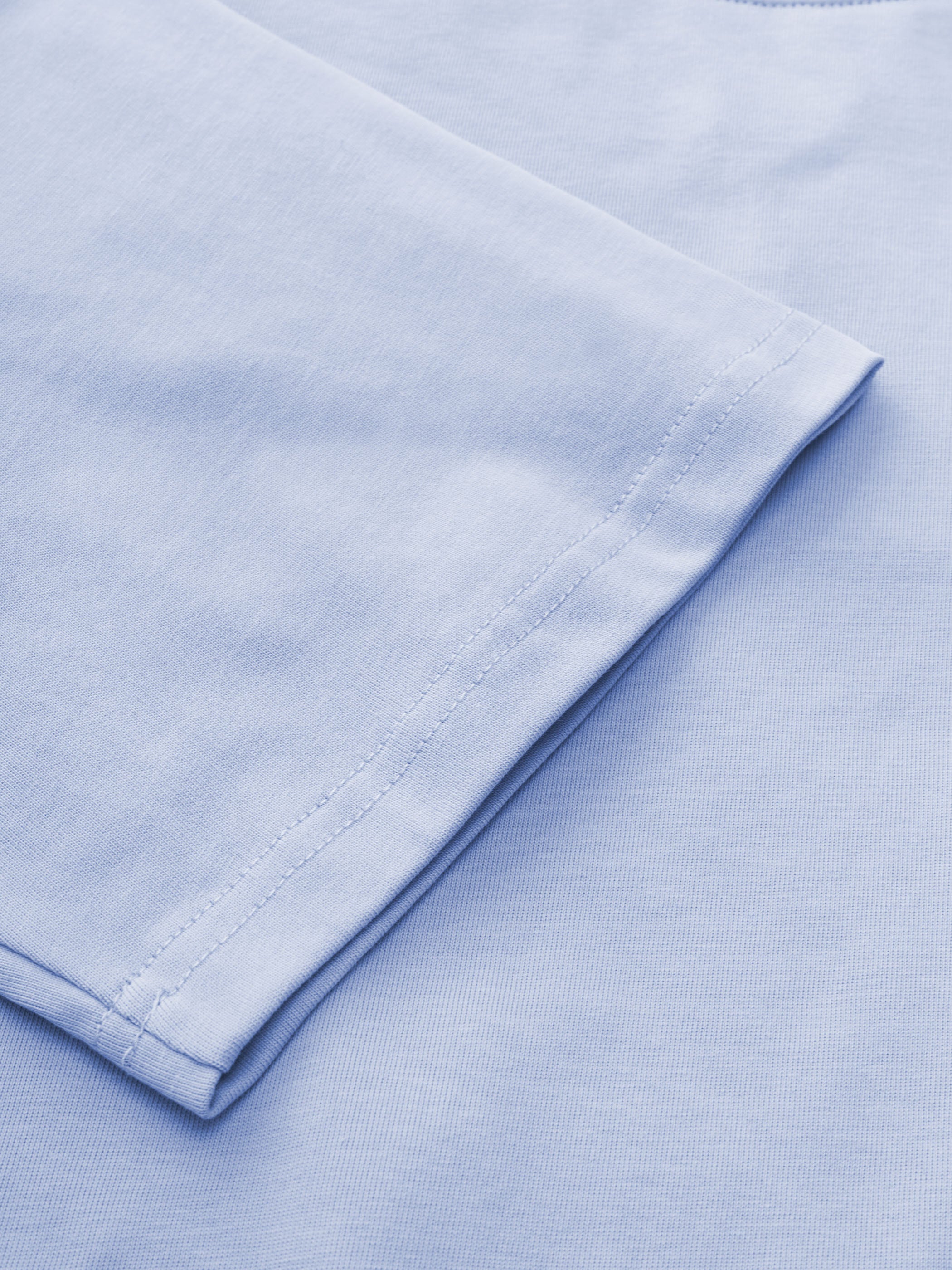 マカロンカラーのTシャツの「BRAVE MOUNTAIN ATHLETIC CLUB」フロッキープリントのクローズアップ、テクスチャとディテールを強調。