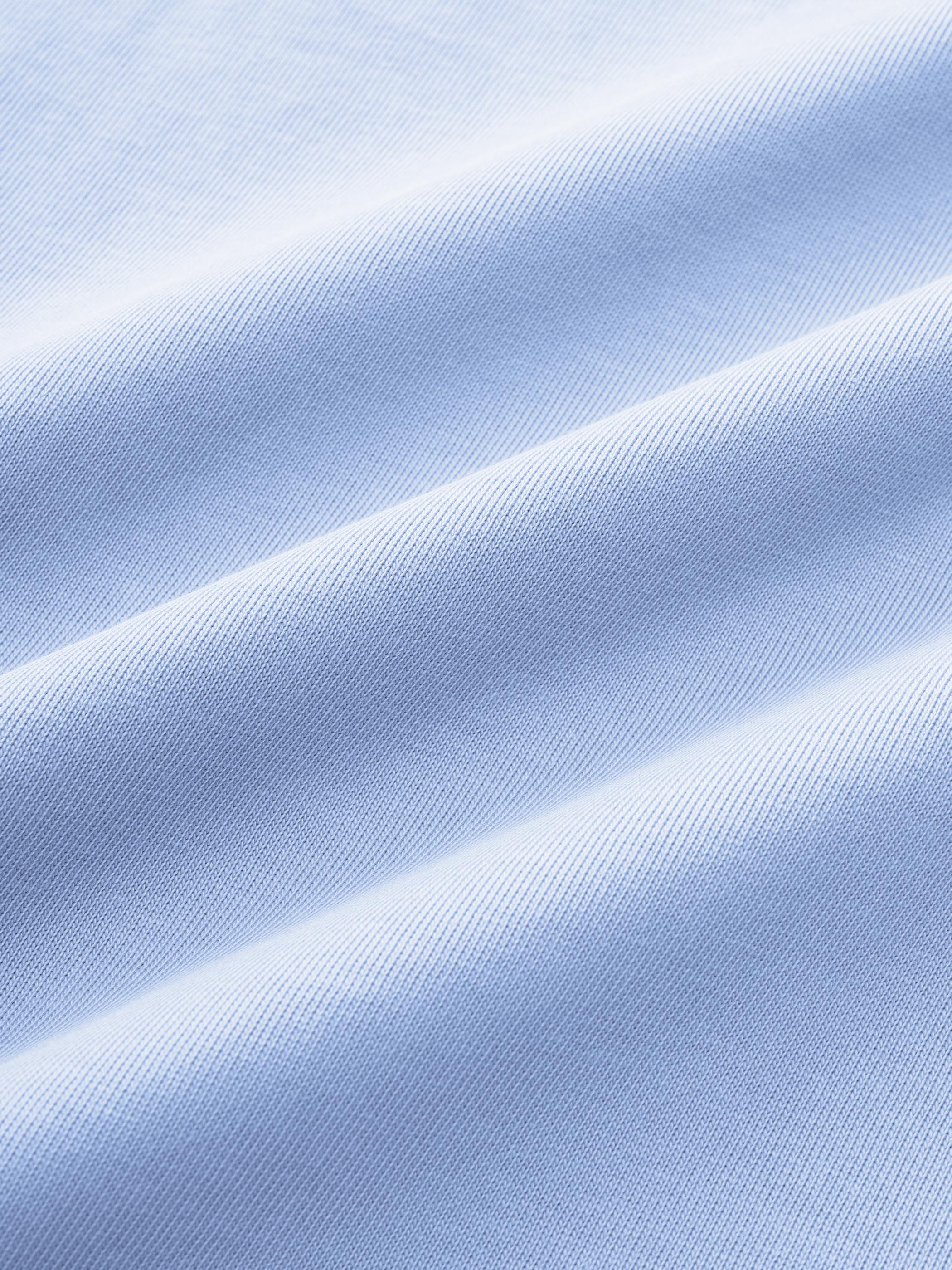 マカロンカラーのTシャツの「BRAVE MOUNTAIN ATHLETIC CLUB」フロッキープリントのクローズアップ、テクスチャとディテールを強調。