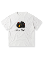 コンリホワイトカメラプリントTシャツの全体像、クラシックなカメラモチーフとルーズフィットシルエットを示す。