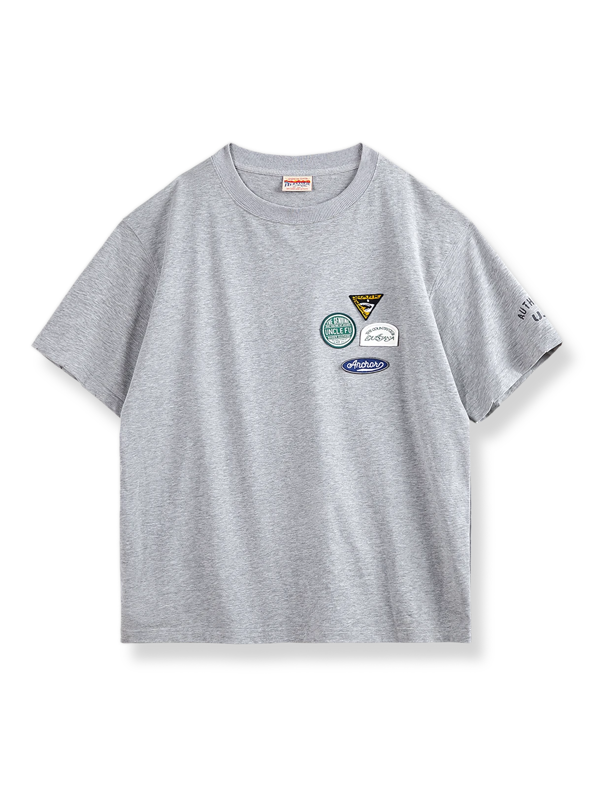 左胸に4つのカラフルな刺繍バッジが付いたグレーベースの半袖Tシャツ。