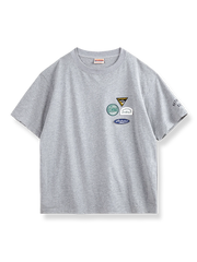 左胸に4つのカラフルな刺繍バッジが付いたグレーベースの半袖Tシャツ。
