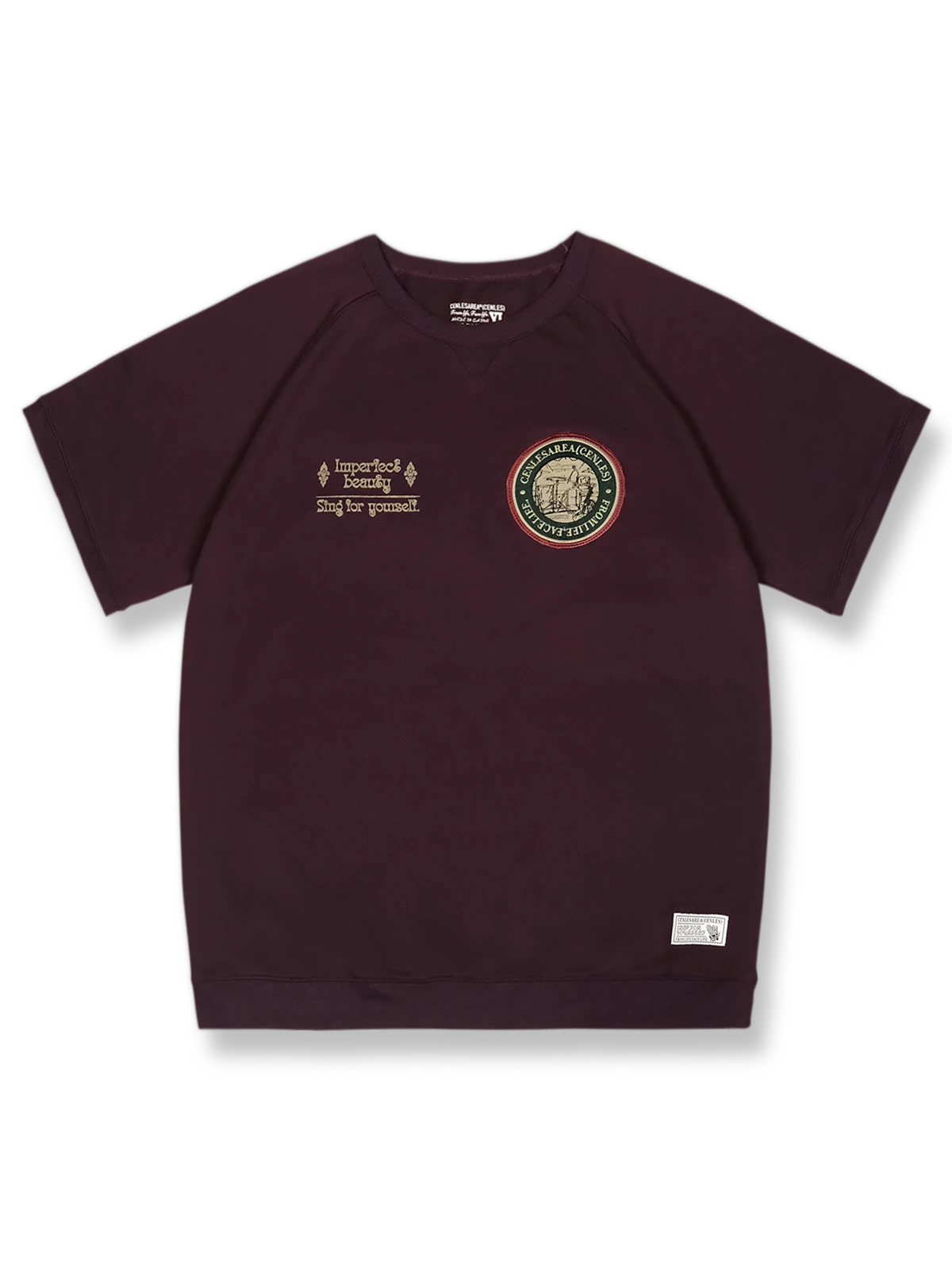 胸元に刺繍バッジが付いたラグランスリーブの半袖Tシャツ。