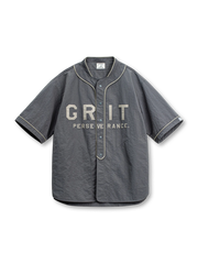 「GRIT PERSEVERANCE」パッチとホログラムボタンが特徴の90年代風軽量ベースボールシャツ。