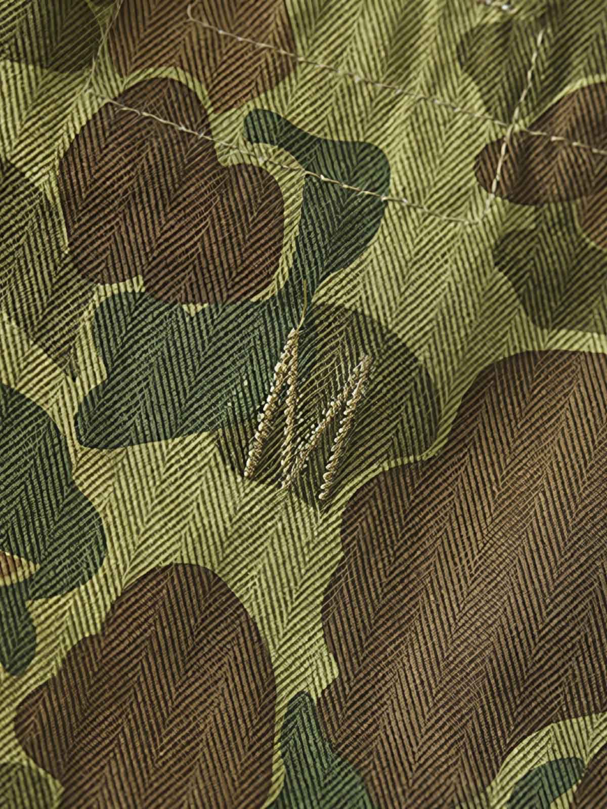 製品画像: 迷彩柄ツイルデニム生地の砲兵防護プルオーバーパーカー復刻バージョンの正面画像。
詳細画像: 大きなフードと三層前立てデザインのディテール特写。機能性とヴィンテージ感が際立つディテール。
