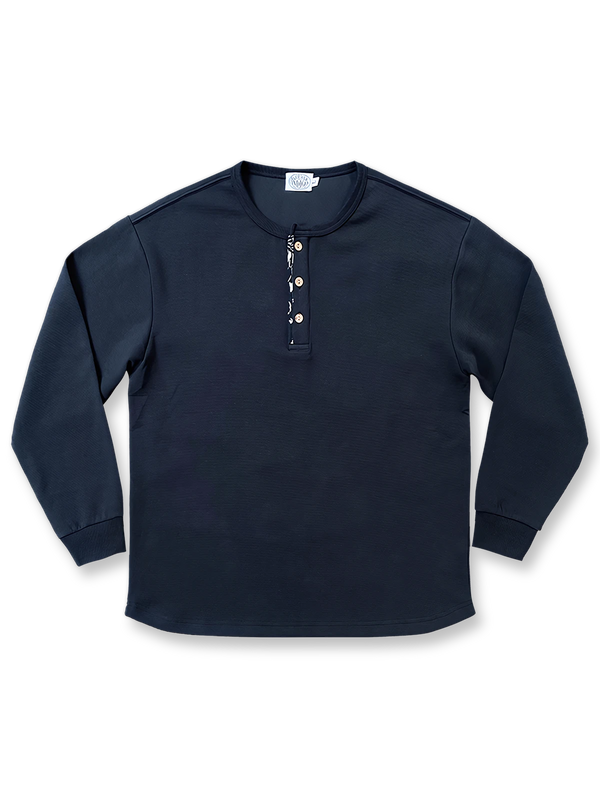 藍染古布襟とワッフル編みを施したヘンリーネック長袖Tシャツ。カーブ裾とココナッツボタンが特徴のユニセックスデザイン。