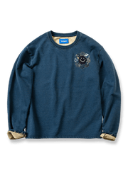インディゴ染めスウェットにスマイリーフラワー刺繍と古着風パッチワークを施したデザイン。