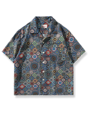 万華鏡柄プリントとルーズフィットが特徴のポリエステル製半袖アロハシャツ、胸ポケットとココナッツボタン付き