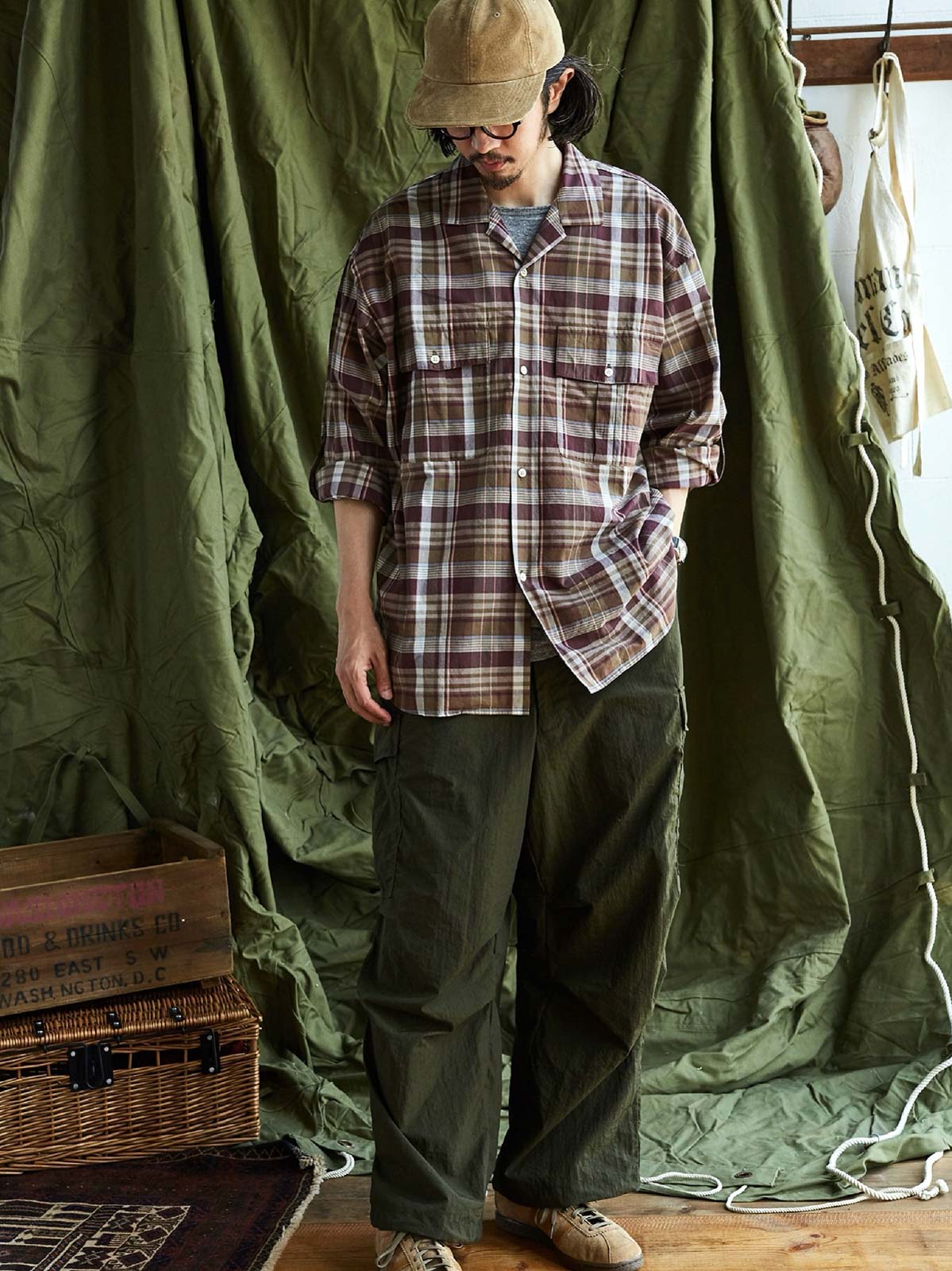 詳細画像: キューバンカラーと胸前のフラップポケットのディテール。チェック柄の鮮明さとシャツの質感を強調。
モデル画像: モデルがMADRAS (マドラス) チェック柄シャツを着用したスタイリング例。実際の着用感やフィット感を視覚的に伝える。