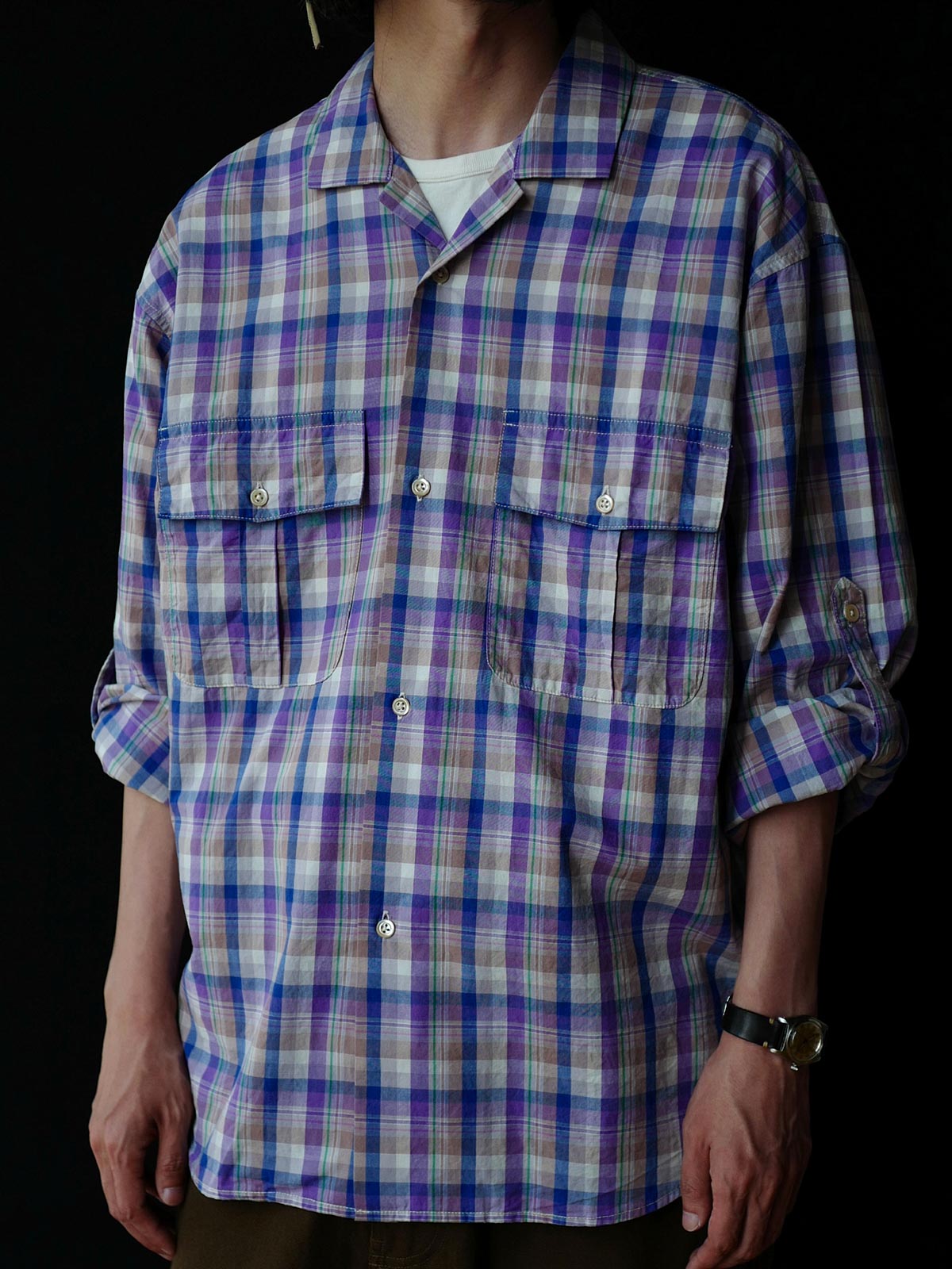 詳細画像: キューバンカラーと胸前のフラップポケットのディテール。チェック柄の鮮明さとシャツの質感を強調。
モデル画像: モデルがMADRAS (マドラス) チェック柄シャツを着用したスタイリング例。実際の着用感やフィット感を視覚的に伝える。