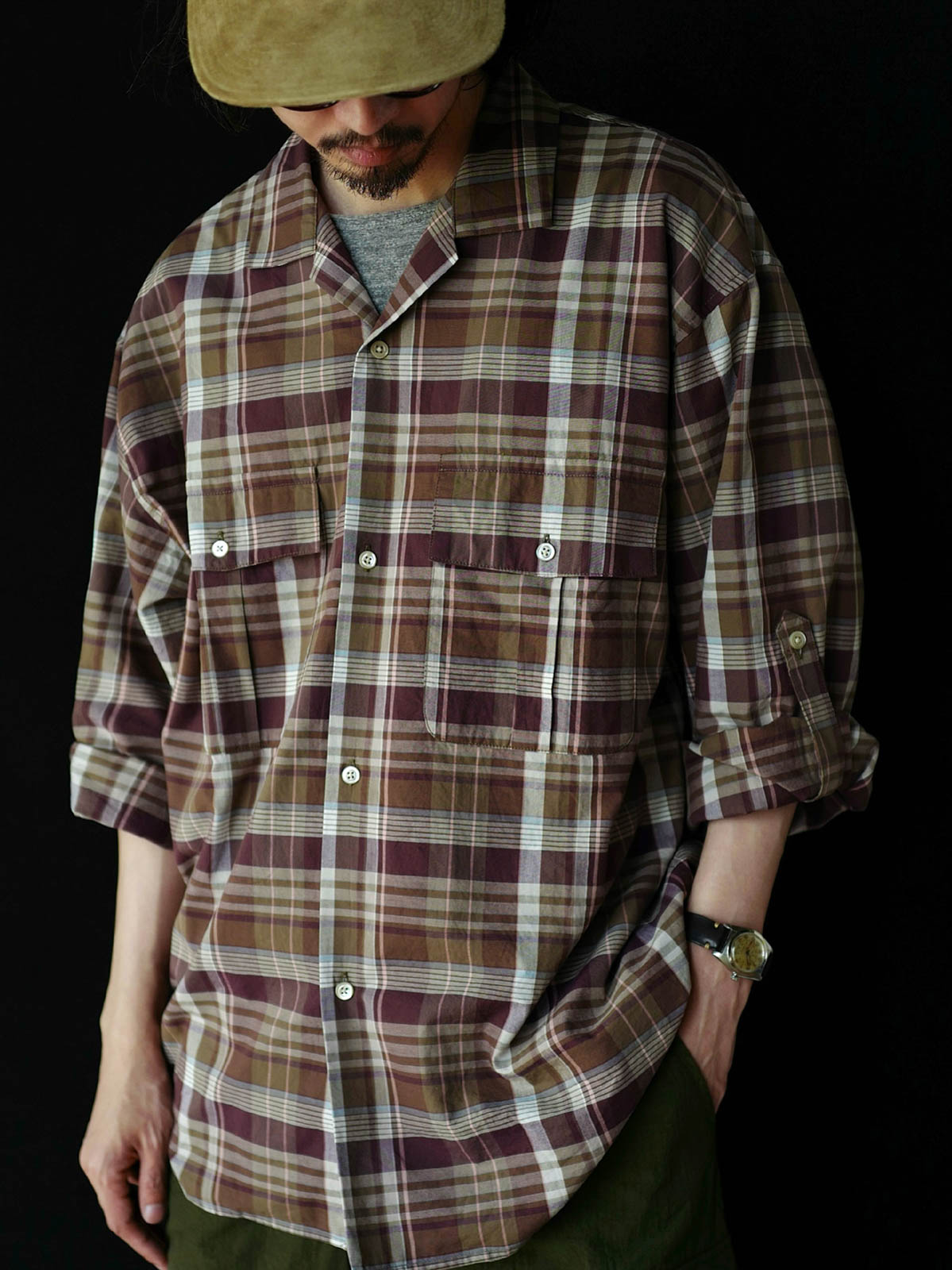 詳細画像: キューバンカラーと胸前のフラップポケットのディテール。チェック柄の鮮明さとシャツの質感を強調。
モデル画像: モデルがMADRAS (マドラス) チェック柄シャツを着用したスタイリング例。実際の着用感やフィット感を視覚的に伝える。