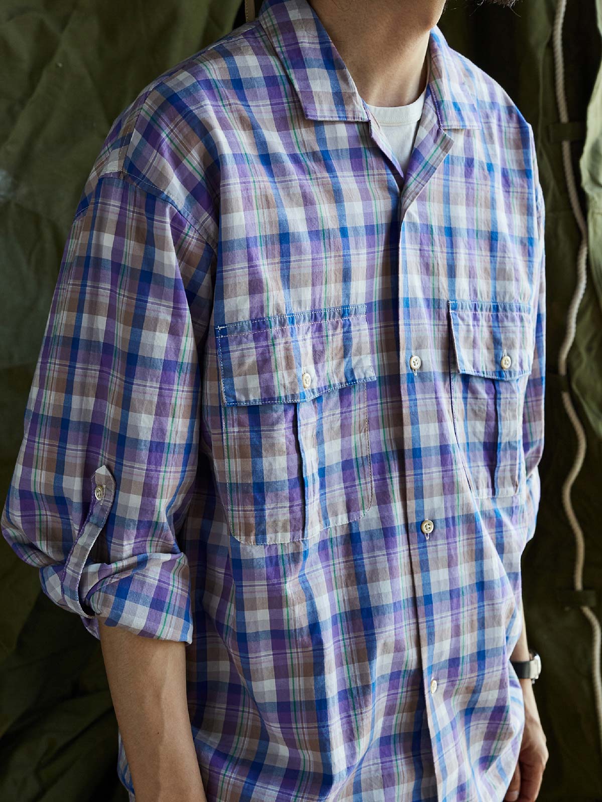 詳細画像: キューバンカラーと胸前のフラップポケットのディテール。チェック柄の鮮明さとシャツの質感を強調。
モデル画像: モデルがMADRAS (マドラス) チェック柄シャツを着用したスタイリング例。実際の着用感やフィット感を視覚的に伝える。