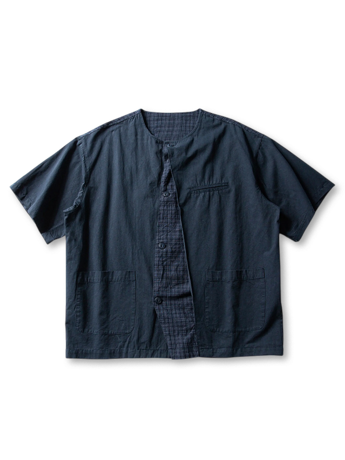 チェックパネルと同色ポケットを配したノーカラーデザインの薄手コットンレイヤードシャツ