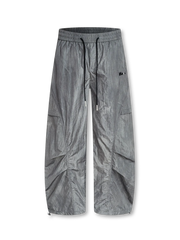  軽量ナイロン素材とカーブシームが特徴のパラシュート降下兵ルーツのワイドパンツ。ドローストリングウエストで調節可能、シンプルなTシャツとミリタリーブーツに合うストリートスタイル。