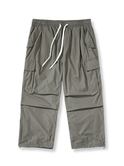 多ポケットとドローストリングウエストを備えた軽量ポリエステル製パラシュートパンツ。ワイドシルエットで動きやすく、ヴィンテージ感あるデザイン。