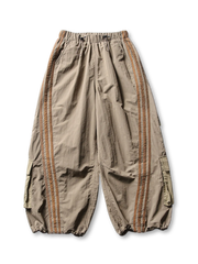 ウエスト全周ゴム仕様のパラシュートワイドカーゴパンツ。斜め3本ラインと大容量ポケットが特徴。裾アジャスターでシルエット調整可能。防水・防風・速乾素材使用でアウトドアにも最適。