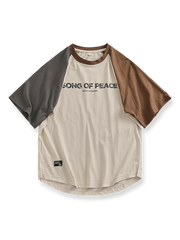 パッチワークとラグランスリーブ、カーブヘムが特徴の「SONG OF PEACE」プリント入りコットンTシャツ