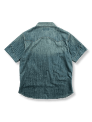 ウェスタンスタイルのデニム半袖シャツの正面ビュー。典型的なダブルポケットと精密なステッチワークが特徴で、アシンメトリックな裾とサイドスリットが加えられたモダンなデザインです。